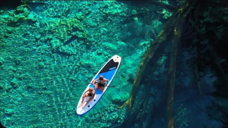 Vista aérea con dron de una canoa tradicional navegando sobre las aguas cristalinas del lago Paisu Pok en la isla de Peleng.
