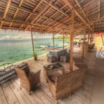 Terraza de madera cubierta frente al mar en Paisupok Lodge Luk Panenteng