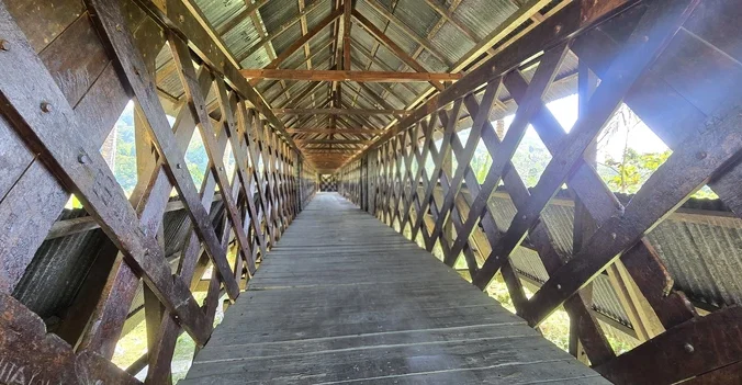 Pasarela interior cubierta del histórico puente colonial de madera de hierro Jembatan Tua en Lobu, ruta Luwuk Ampana.
