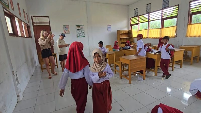 Viajeros compartiendo un momento con alumnos y profesores en el interior de una escuela sobre el mar en una aldea flotante de la etnia Bajau en Indonesia.