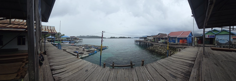 Pasarela de madera sobre el mar turquesa en un asentamiento tradicional de palafitos de la etnia Bajau en Sombori, Sulawesi.