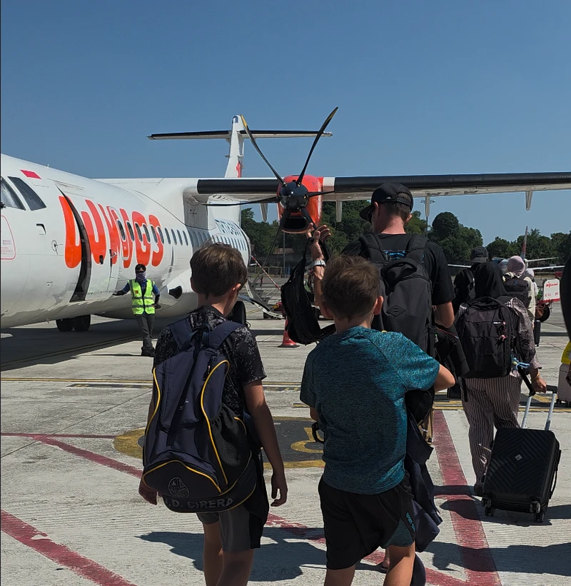 Pasajeros caminando por la pista de aterrizaje para embarcar en un avión turbohélice ATR 72 de Wings Air en un aeropuerto regional de Sulawesi.