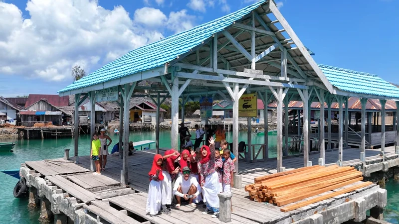 Viajero interactuando de forma ética con niños de la etnia Bajau a la salida de su escuela flotante de madera en Sulawesi.