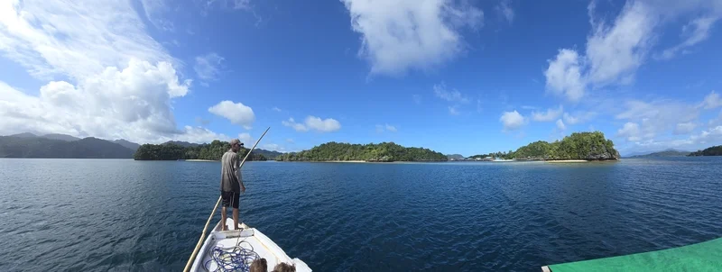 Viajero llegando en lancha tradicional de madera a un asentamiento flotante de la etnia Bajau sobre pilotes en el mar de Sulawesi.