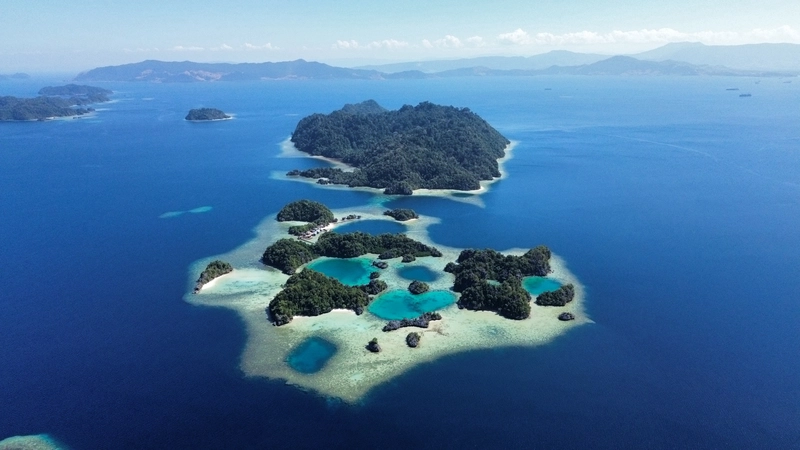 Vista panorámica aérea con dron de las formaciones kársticas, lagunas turquesas y arrecifes de la bahía de Sombori en Sulawesi.